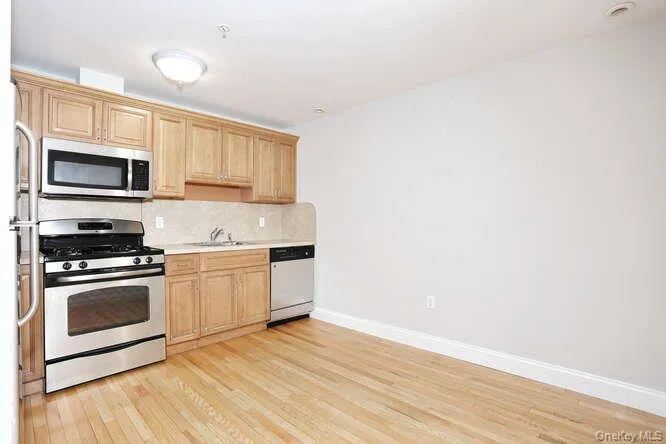 Kitchen with stainless steel appliances, light wood-style floors, a sink, and baseboards Kitchen with stainless steel appliances, light wood-style floors, a sink, and baseboards