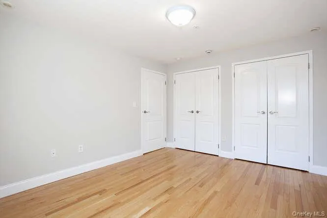 Unfurnished bedroom featuring multiple closets, baseboards, and light wood-style floors Unfurnished bedroom featuring multiple closets, baseboards, and light wood-style floors