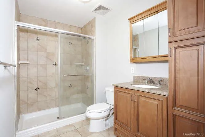 Full bath with toilet, a shower stall, vanity, and tile patterned floors Full bath with toilet, a shower stall, vanity, and tile patterned floors