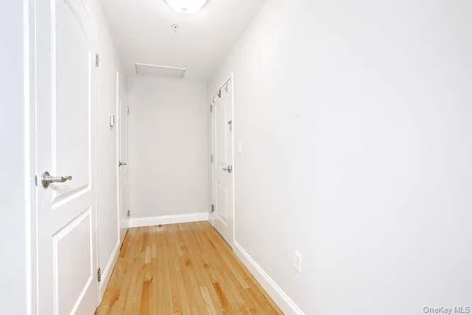 Corridor with light wood-style flooring, attic access, and baseboards Corridor with light wood-style flooring, attic access, and baseboards