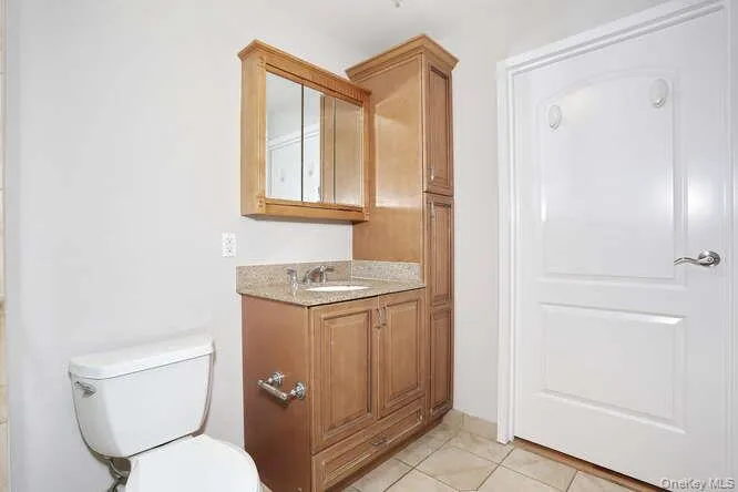 Bathroom with toilet, vanity, and tile patterned flooring Bathroom with toilet, vanity, and tile patterned flooring
