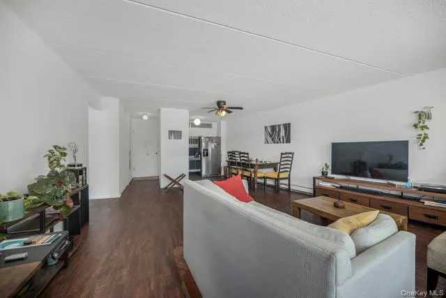 Spacious living area featuring rich wood-finish flooring and bright white walls Spacious living area featuring rich wood-finish flooring and bright white walls