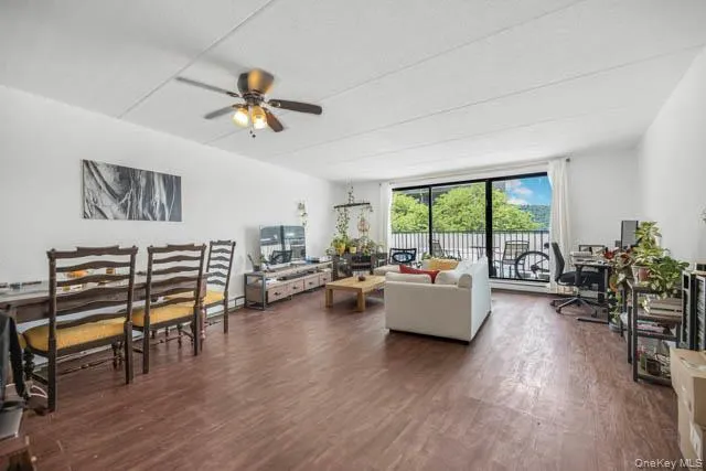 Spacious open-concept living area featuring wood-finish flooring and a ceiling fan with integrated lighting Spacious open-concept living area featuring wood-finish flooring and a ceiling fan with integrated lighting