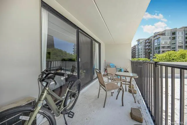 Private outdoor balcony with concrete flooring, a dark metal railing, and a sliding glass door Private outdoor balcony with concrete flooring, a dark metal railing, and a sliding glass door