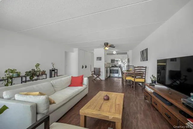 Open-concept living area featuring wood-finish flooring, white walls, and a ceiling fan Open-concept living area featuring wood-finish flooring, white walls, and a ceiling fan