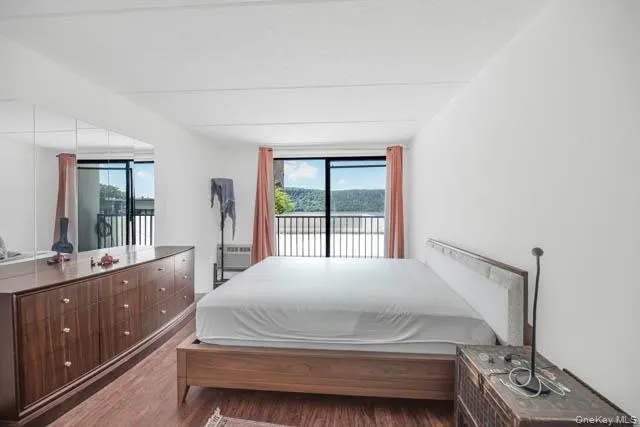 Bedroom with wood-finish flooring and a built-in mirrored wall Bedroom with wood-finish flooring and a built-in mirrored wall