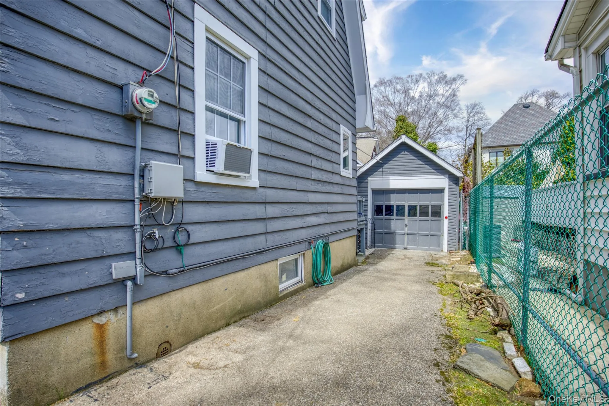 Detached single-car garage featuring a paneled door, situated at the end of a paved driveway Detached single-car garage featuring a paneled door, situated at the end of a paved driveway