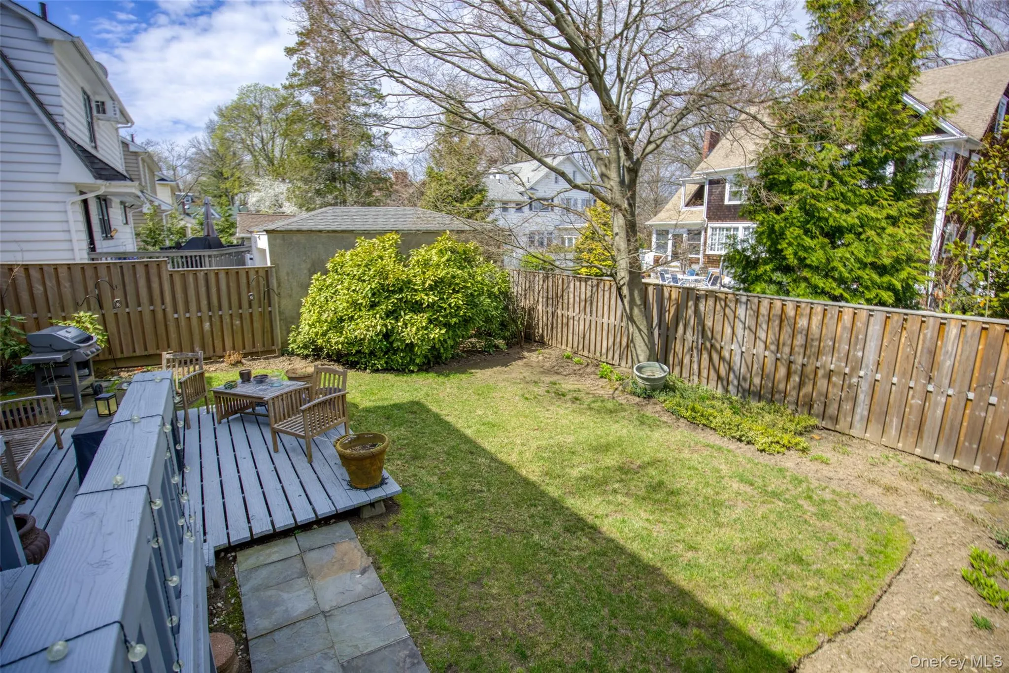 Expansive backyard featuring a gray-painted wood deck, a manicured lawn, and natural wood privacy fencing Expansive backyard featuring a gray-painted wood deck, a manicured lawn, and natural wood privacy fencing