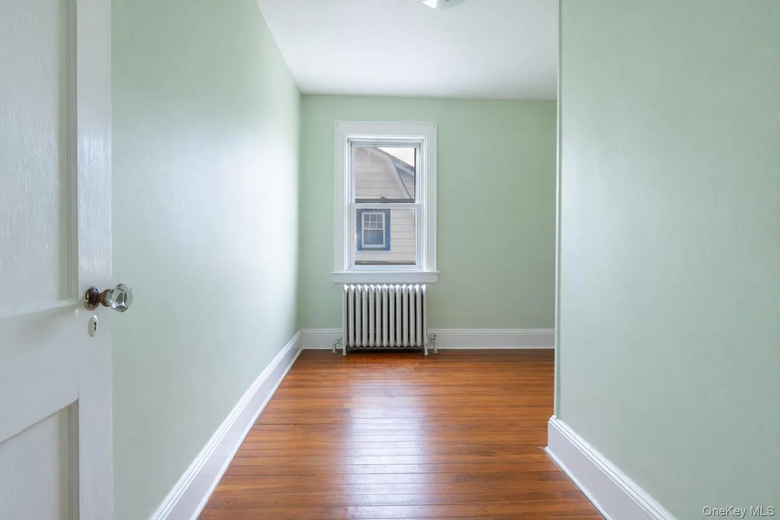 Hardwood flooring throughout a room with light green walls and white trim Hardwood flooring throughout a room with light green walls and white trim
