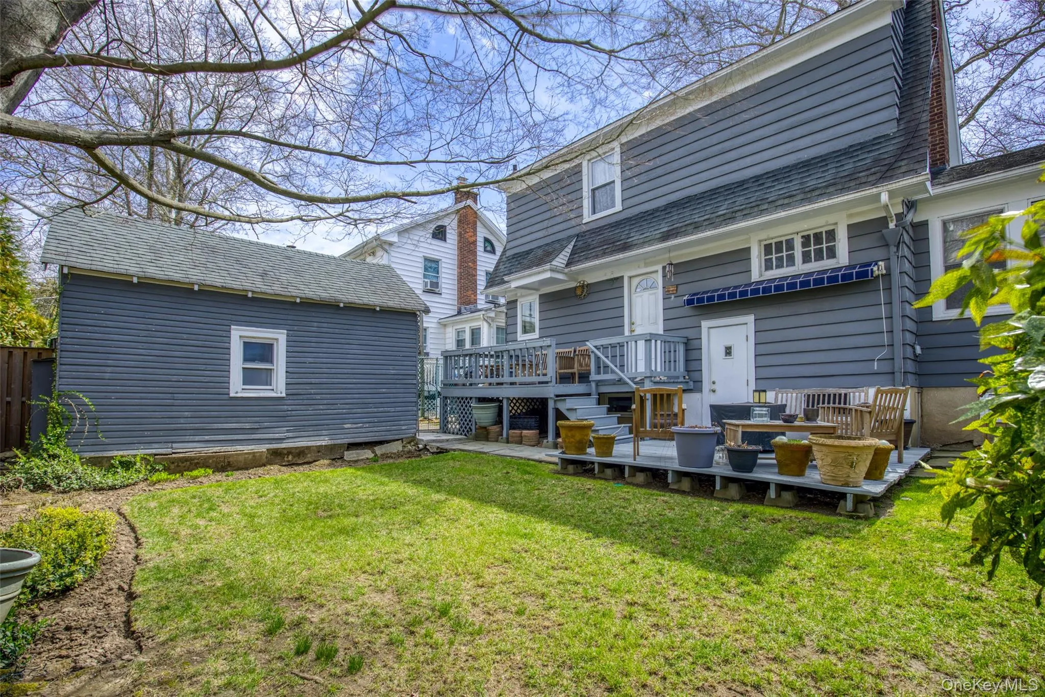 Expansive backyard featuring a manicured lawn, a detached storage shed with horizontal siding, and a multi-level deck Expansive backyard featuring a manicured lawn, a detached storage shed with horizontal siding, and a multi-level deck