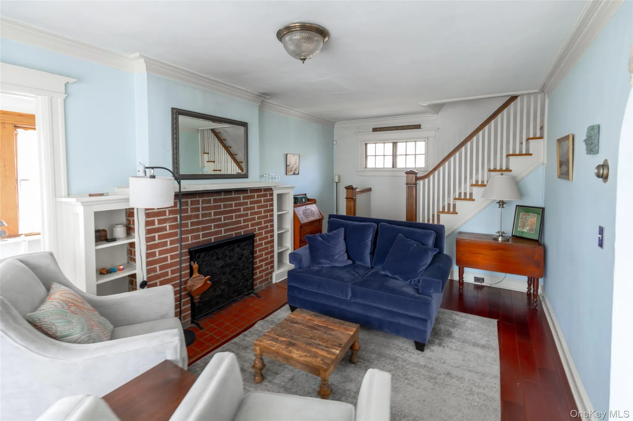 Living area featuring wood-finish flooring and a brick fireplace Living area featuring wood-finish flooring and a brick fireplace