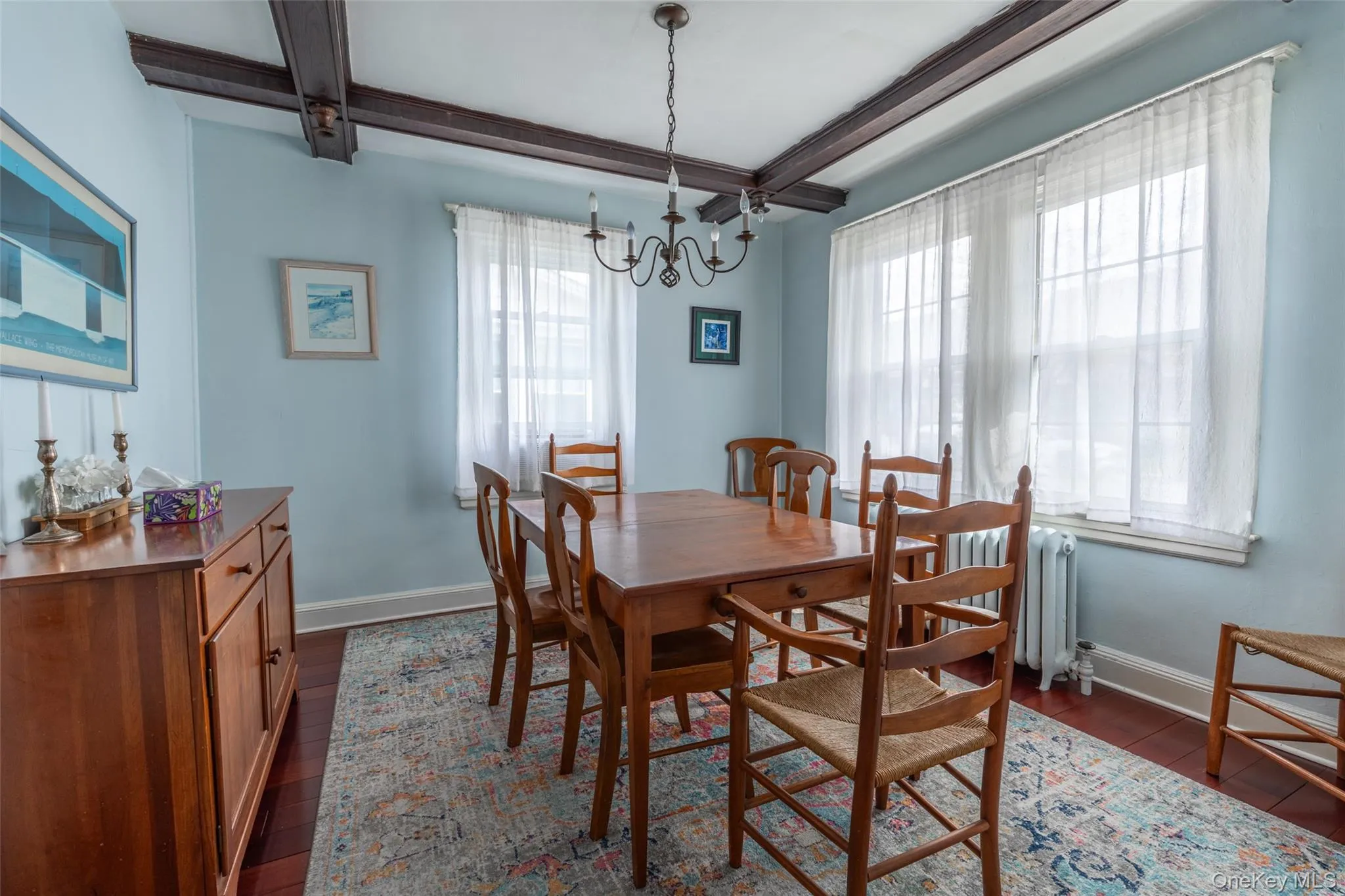 Dining area featuring exposed ceiling beams, wood-finish flooring, and multiple windows Dining area featuring exposed ceiling beams, wood-finish flooring, and multiple windows