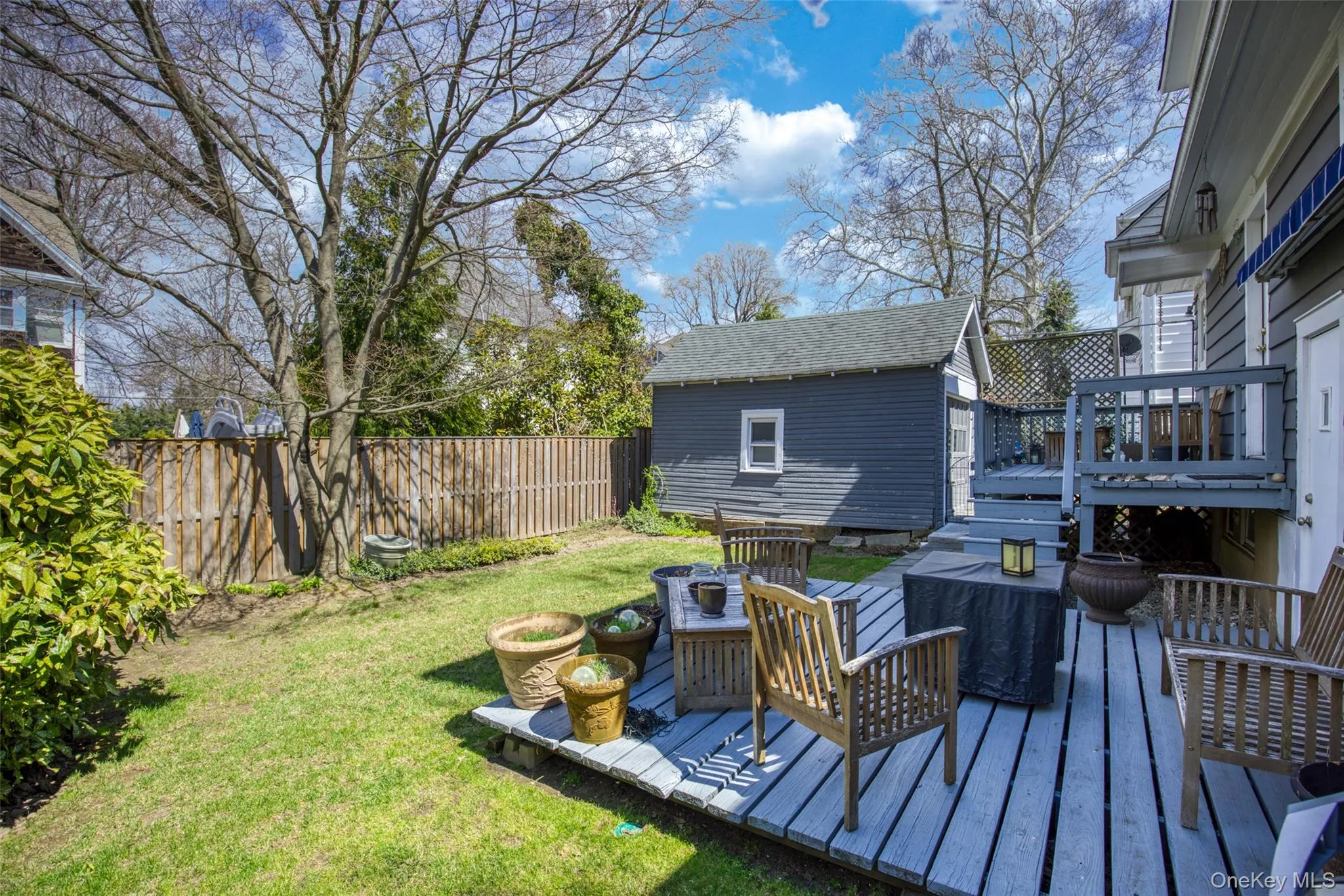 Expansive backyard featuring a manicured lawn, full privacy fencing, established trees, and a multi-level wood-finish deck Expansive backyard featuring a manicured lawn, full privacy fencing, established trees, and a multi-level wood-finish deck