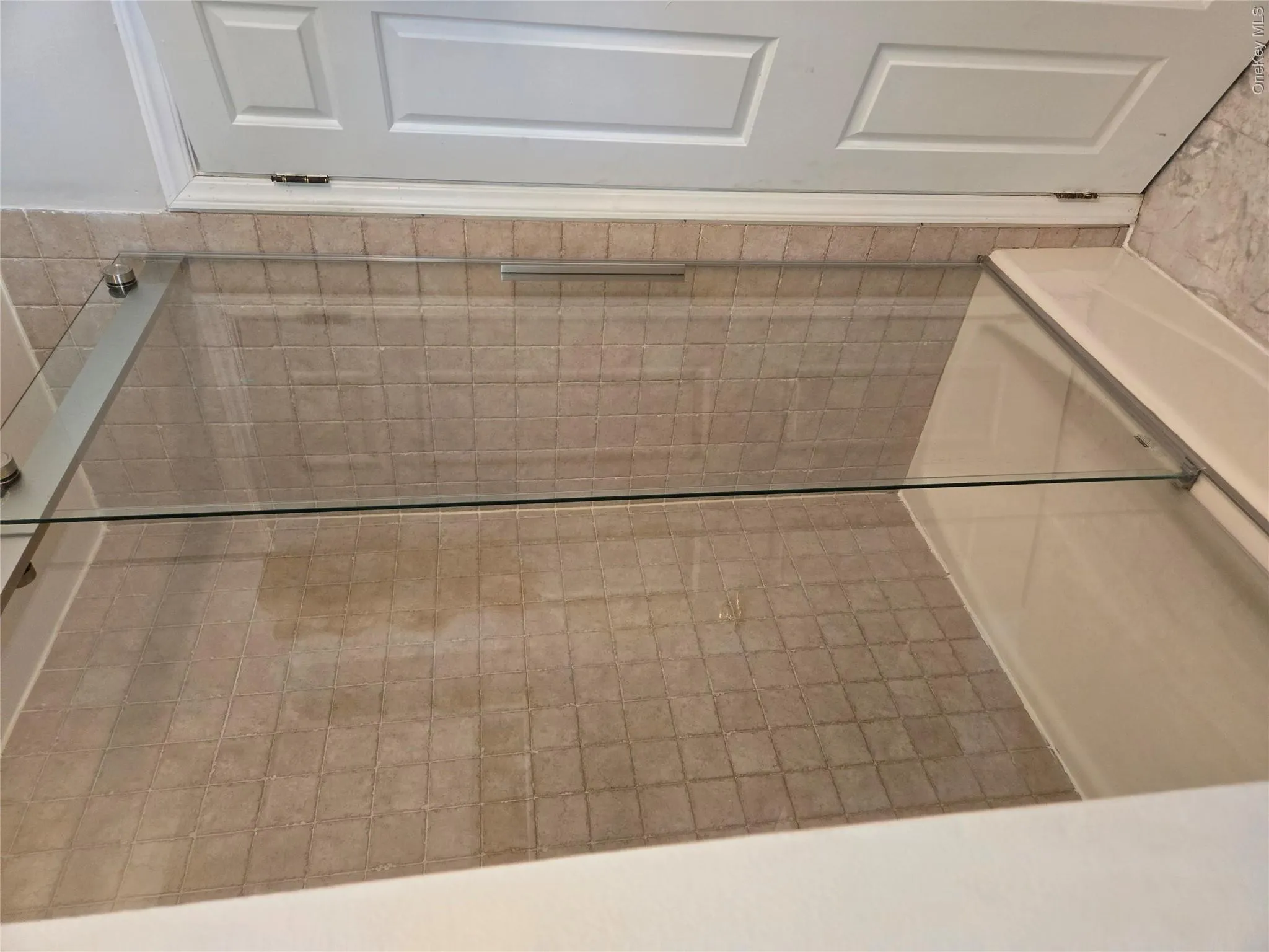 Bathtub with glass sliding enclosure and a beige square tile surround Bathtub with glass sliding enclosure and a beige square tile surround