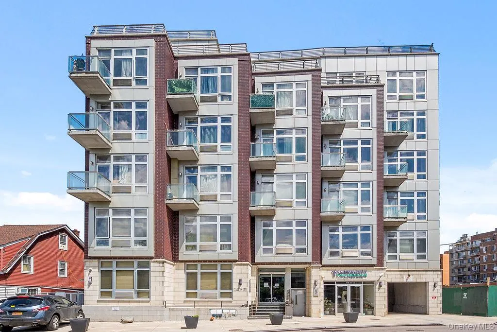 Modern multi-story building featuring brick and panel siding, multiple balconies with glass railings, large windows, and a ground-level entrance with frosted glass doors Modern multi-story building featuring brick and panel siding, multiple balconies with glass railings, large windows, and a ground-level entrance with frosted glass doors