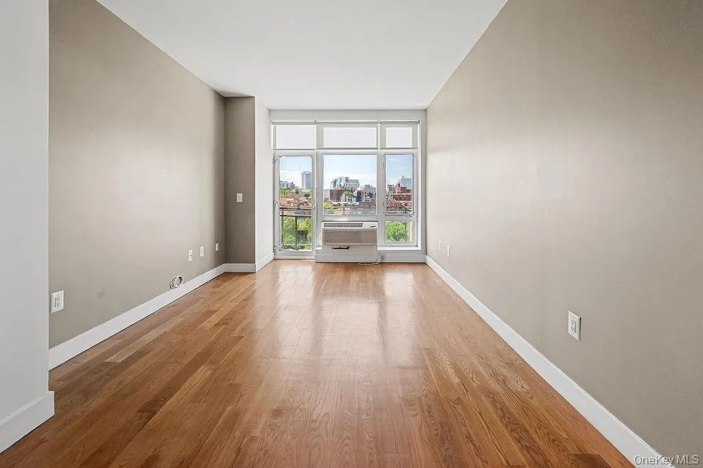 Hardwood flooring extending throughout, complemented by a large window with white framing Hardwood flooring extending throughout, complemented by a large window with white framing