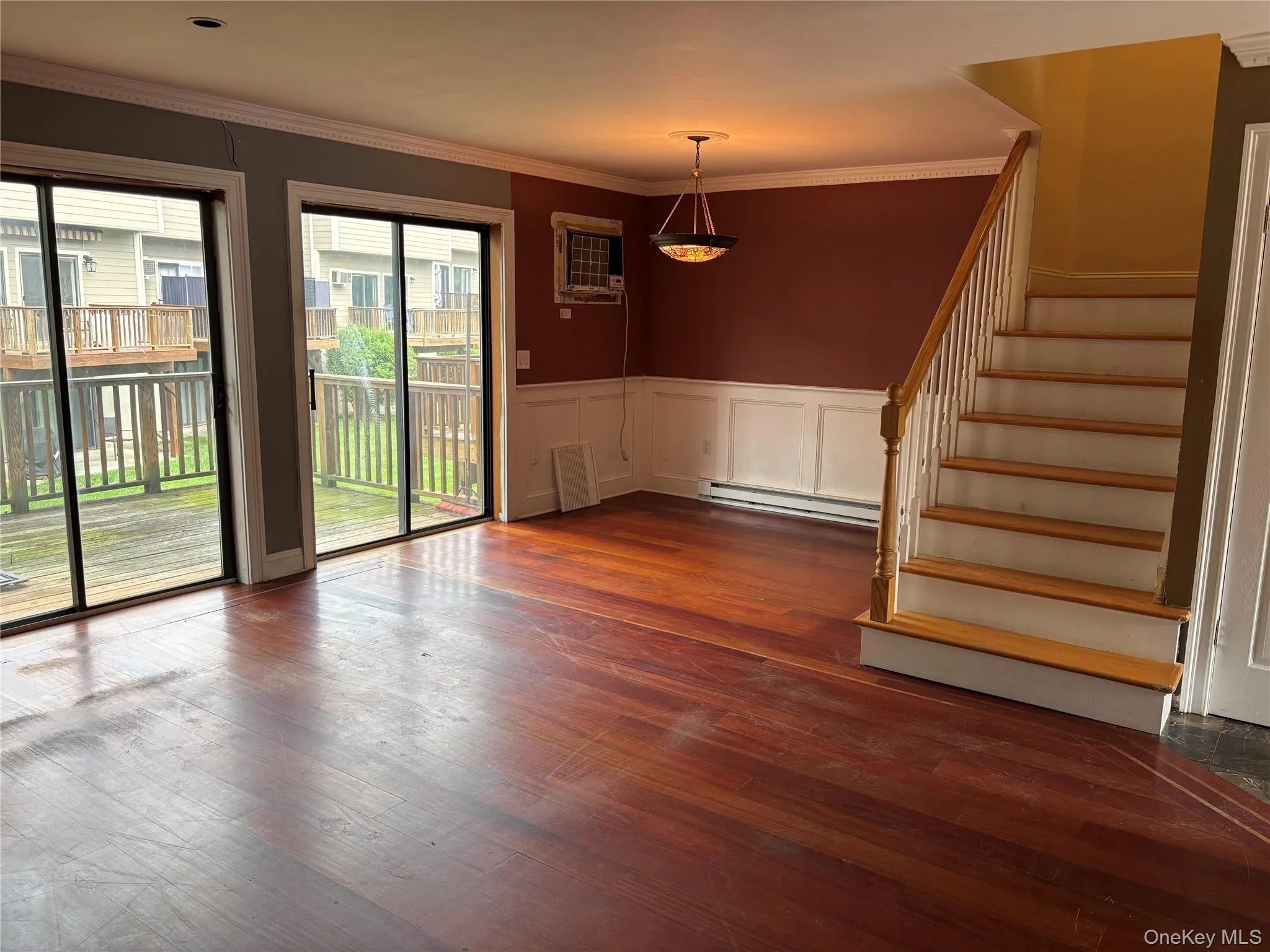 Spacious interior with wood-finish flooring, wainscoting, and crown molding Spacious interior with wood-finish flooring, wainscoting, and crown molding