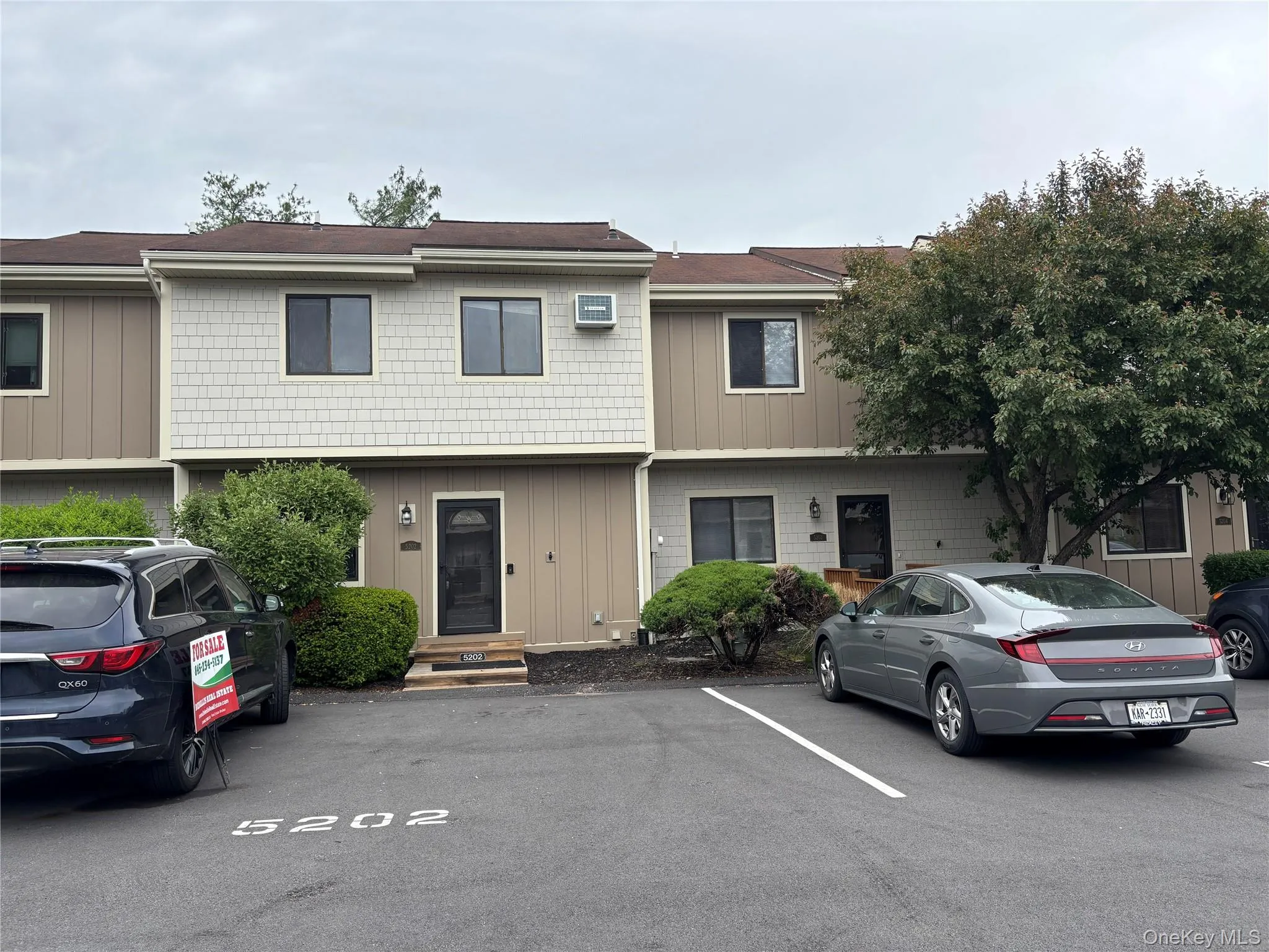 Multi-level townhome featuring a neutral facade with shake and vertical siding Multi-level townhome featuring a neutral facade with shake and vertical siding