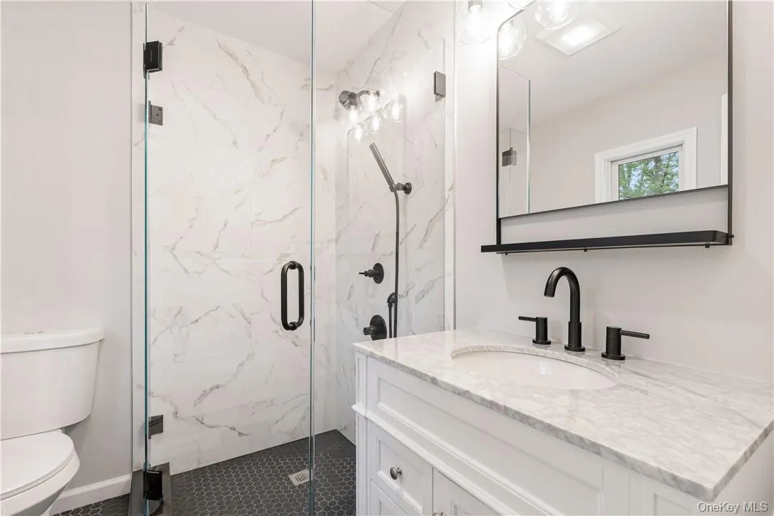 Bathroom featuring vanity, toilet, and an enclosed shower Bathroom featuring vanity, toilet, and an enclosed shower