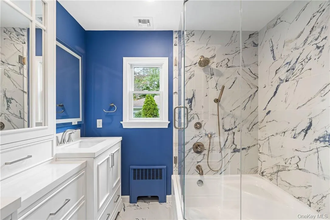 Hall bathroom featuring vanity, tub/shower combo with glass door, lighted touch mirrors Hall bathroom featuring vanity, tub/shower combo with glass door, lighted touch mirrors