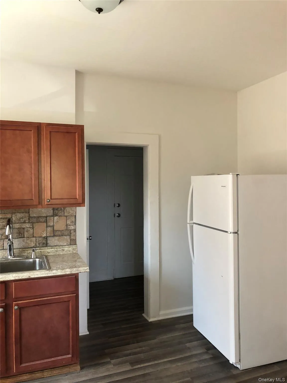 Kitchenette featuring wood-finish flooring, an undermount sink with a gooseneck faucet, a stone-look countertop, and mosaic tile backsplash Kitchenette featuring wood-finish flooring, an undermount sink with a gooseneck faucet, a stone-look countertop, and mosaic tile backsplash