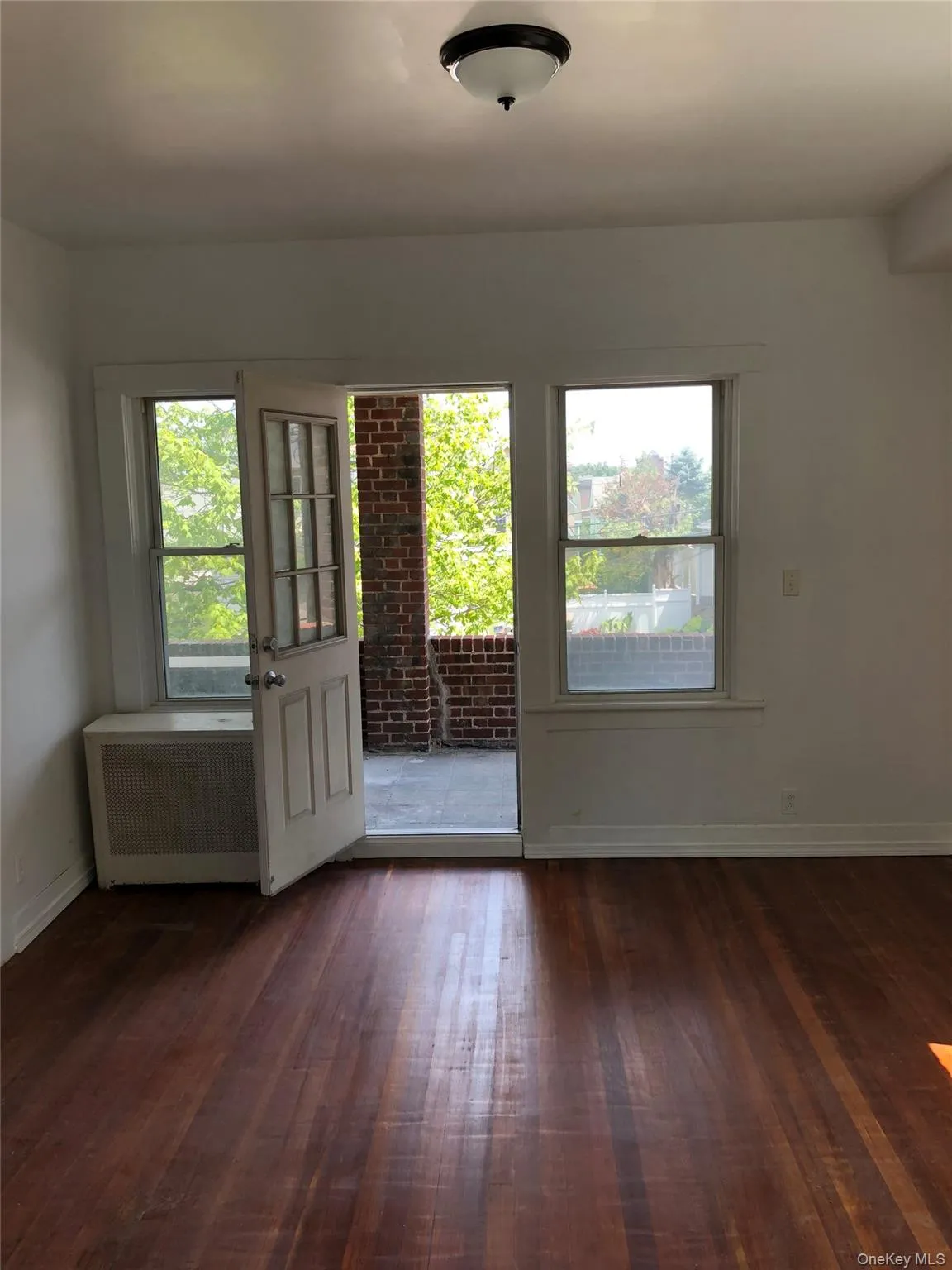 Room featuring wood-finish flooring, white walls, and a semi-flush ceiling light fixture Room featuring wood-finish flooring, white walls, and a semi-flush ceiling light fixture