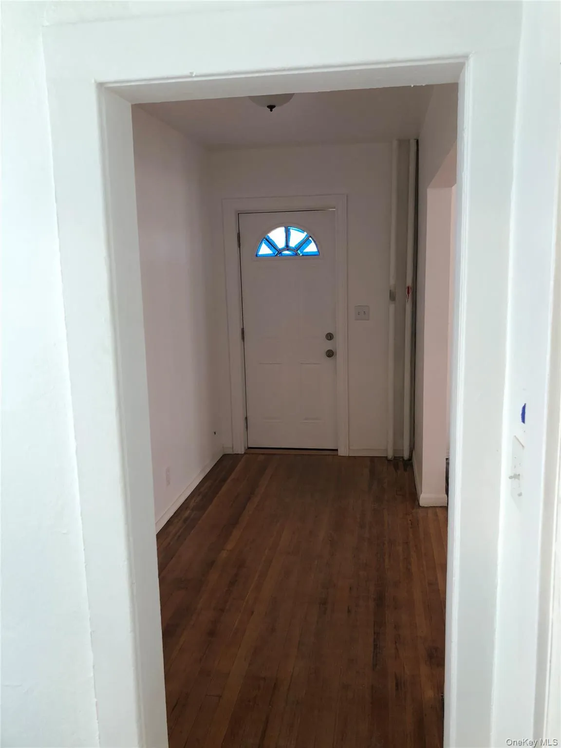 Entryway featuring wood-finish flooring, white walls, and a white door with a decorative transom window Entryway featuring wood-finish flooring, white walls, and a white door with a decorative transom window