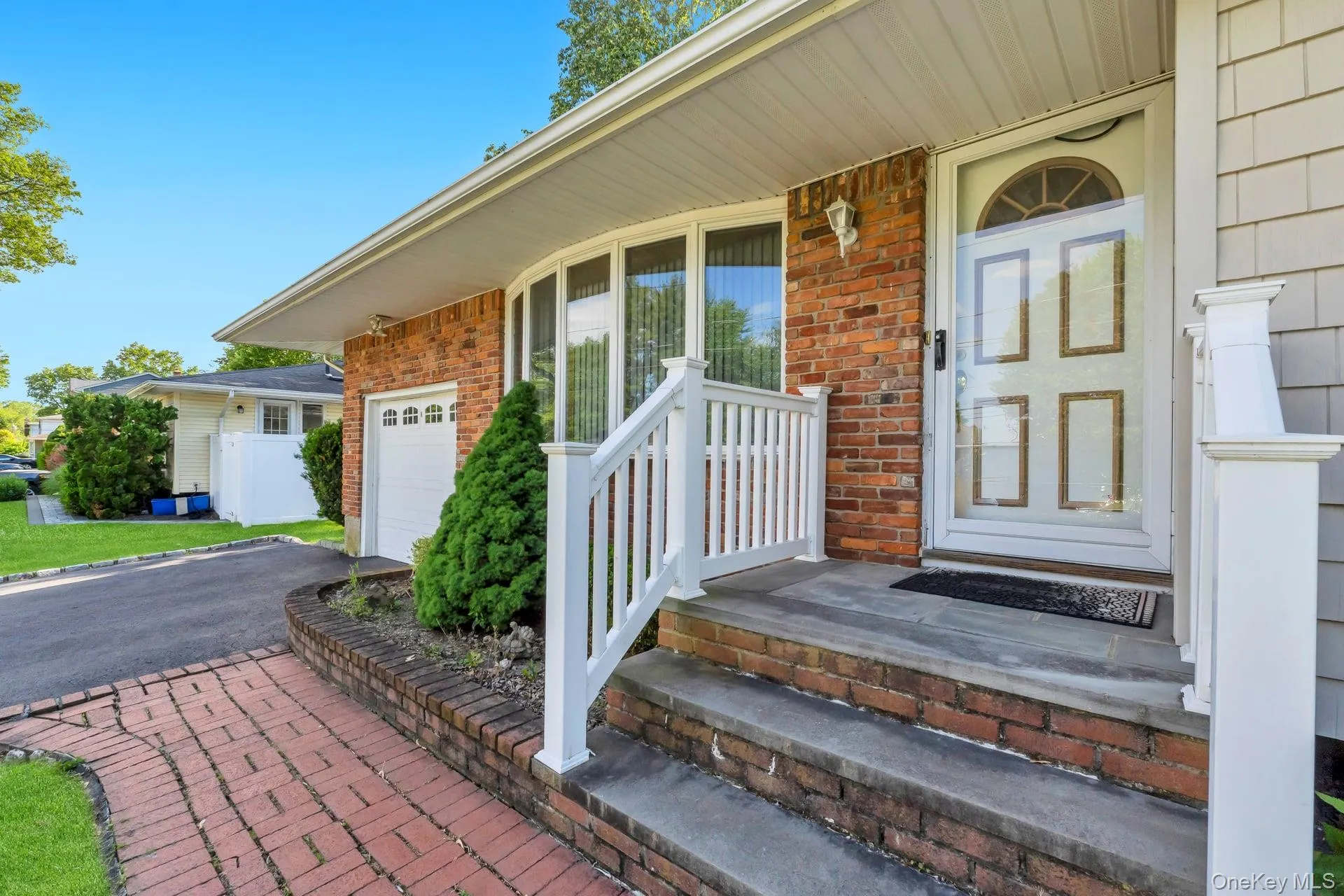 Brick and shingle exterior featuring a curved window bay, white entry door with decorative glass, and a brick paver walkway Brick and shingle exterior featuring a curved window bay, white entry door with decorative glass, and a brick paver walkway