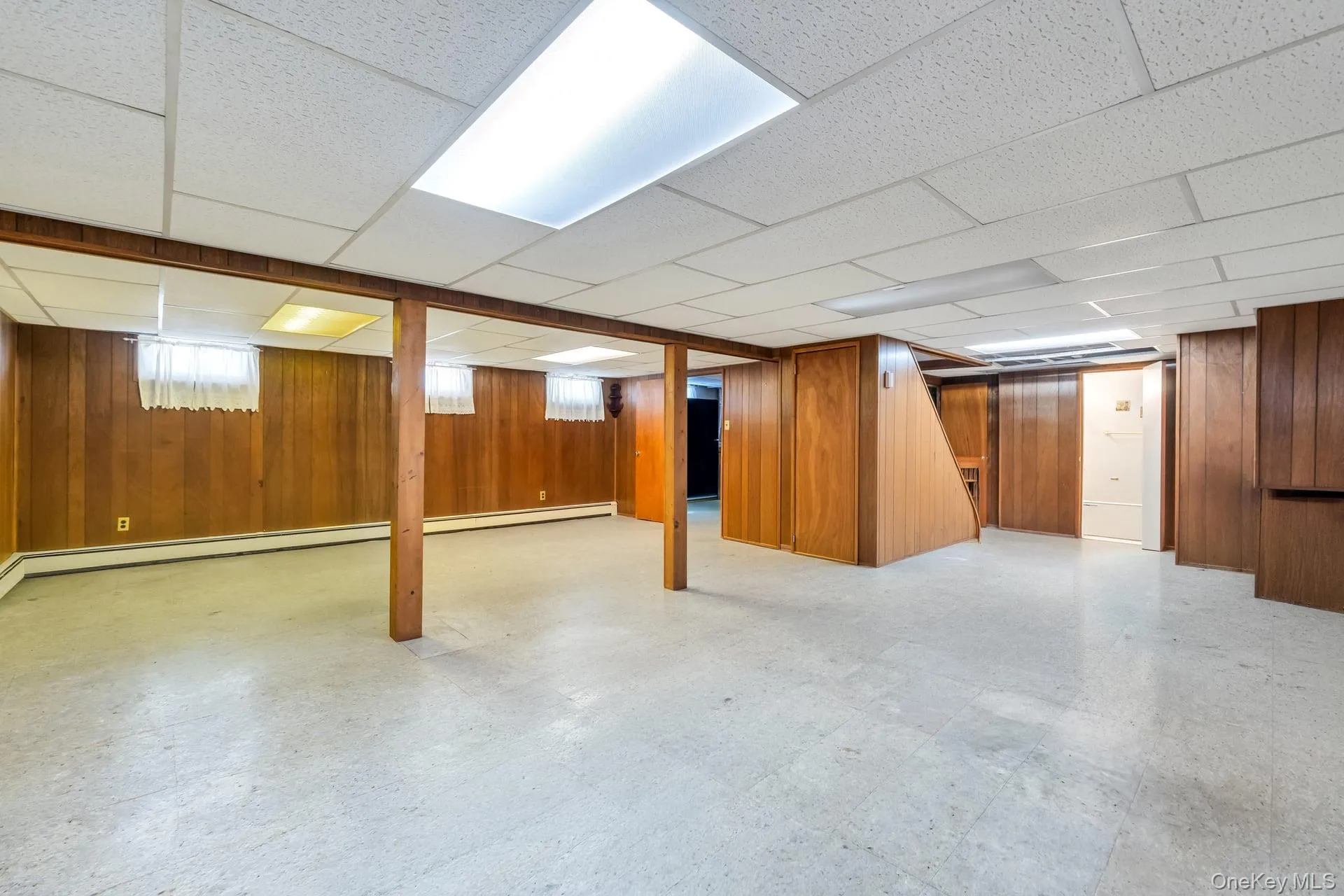 Spacious lower level featuring wood paneling, drop ceiling with integrated lighting, and multiple windows Spacious lower level featuring wood paneling, drop ceiling with integrated lighting, and multiple windows