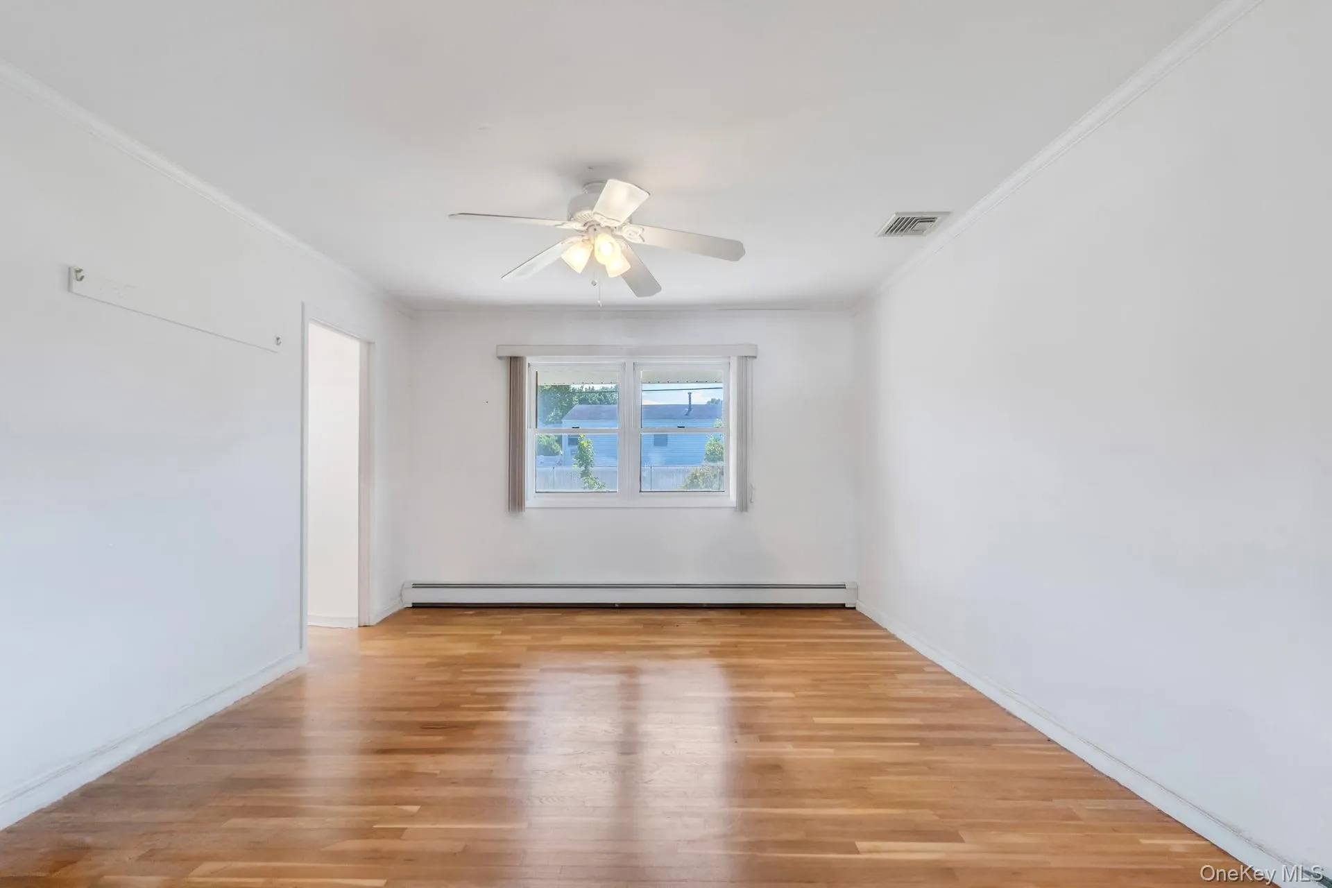 Bright interior space featuring wood-finish flooring, a ceiling fan with integrated lighting, and a multi-pane window Bright interior space featuring wood-finish flooring, a ceiling fan with integrated lighting, and a multi-pane window