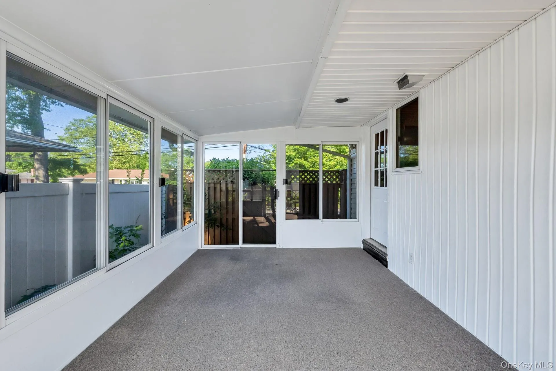 Enclosed porch featuring a white exterior, large windows, a white paneled ceiling, and a grey floor Enclosed porch featuring a white exterior, large windows, a white paneled ceiling, and a grey floor