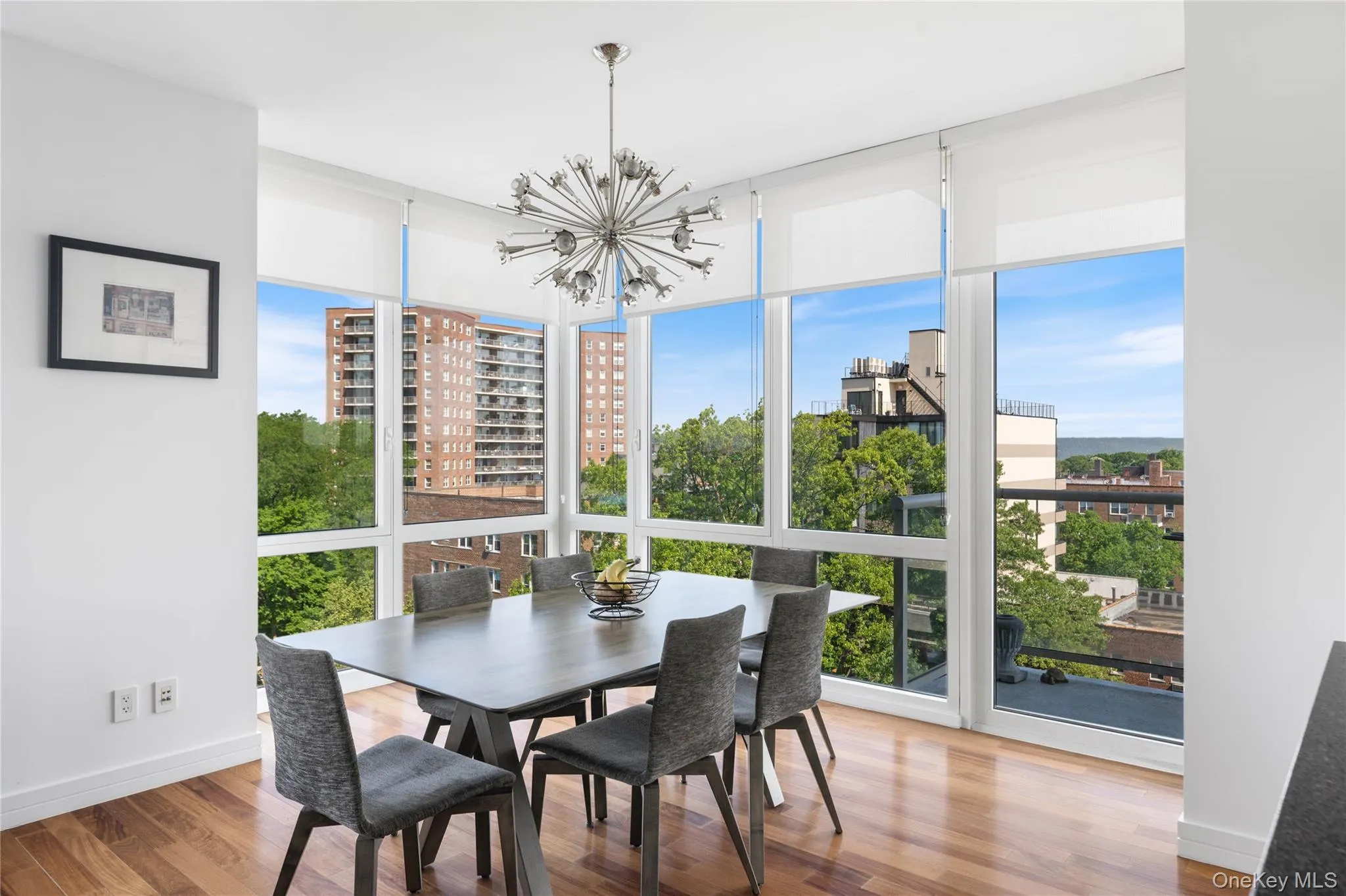 Dining area featuring expansive floor-to-ceiling windows, wood-finish flooring, and a modern sputnik chandelier Dining area featuring expansive floor-to-ceiling windows, wood-finish flooring, and a modern sputnik chandelier