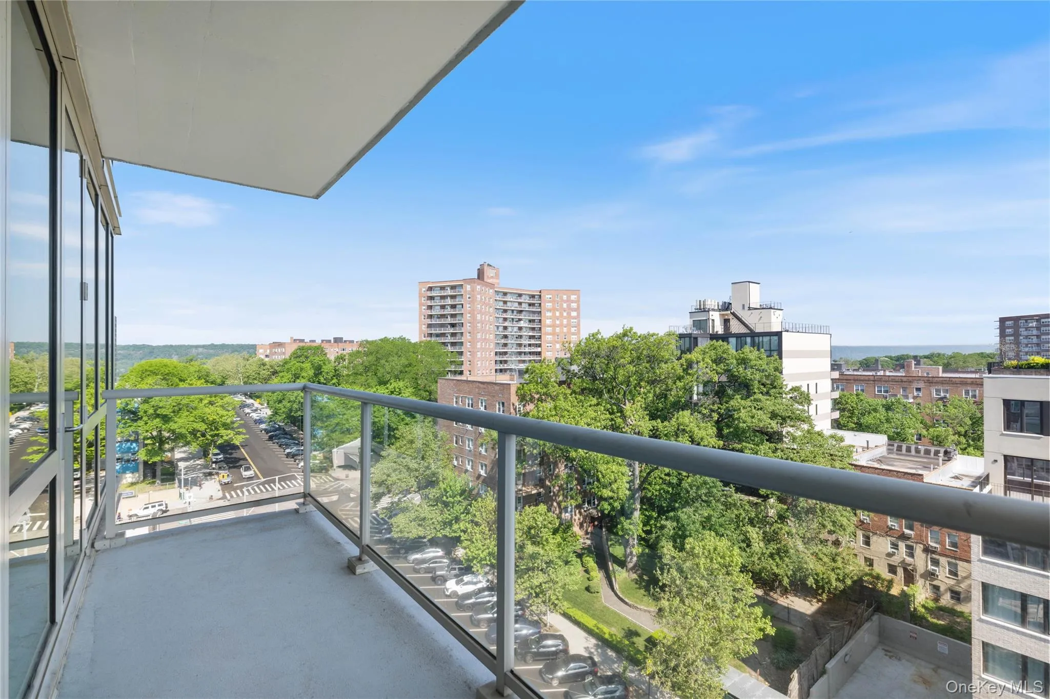 Private balcony featuring a clear glass railing and an expansive urban landscape Private balcony featuring a clear glass railing and an expansive urban landscape