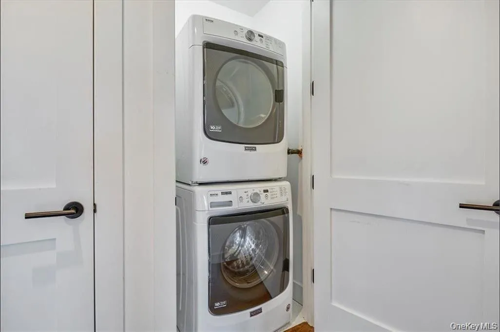 White paneled doors with matte black hardware flank a stacked laundry unit White paneled doors with matte black hardware flank a stacked laundry unit