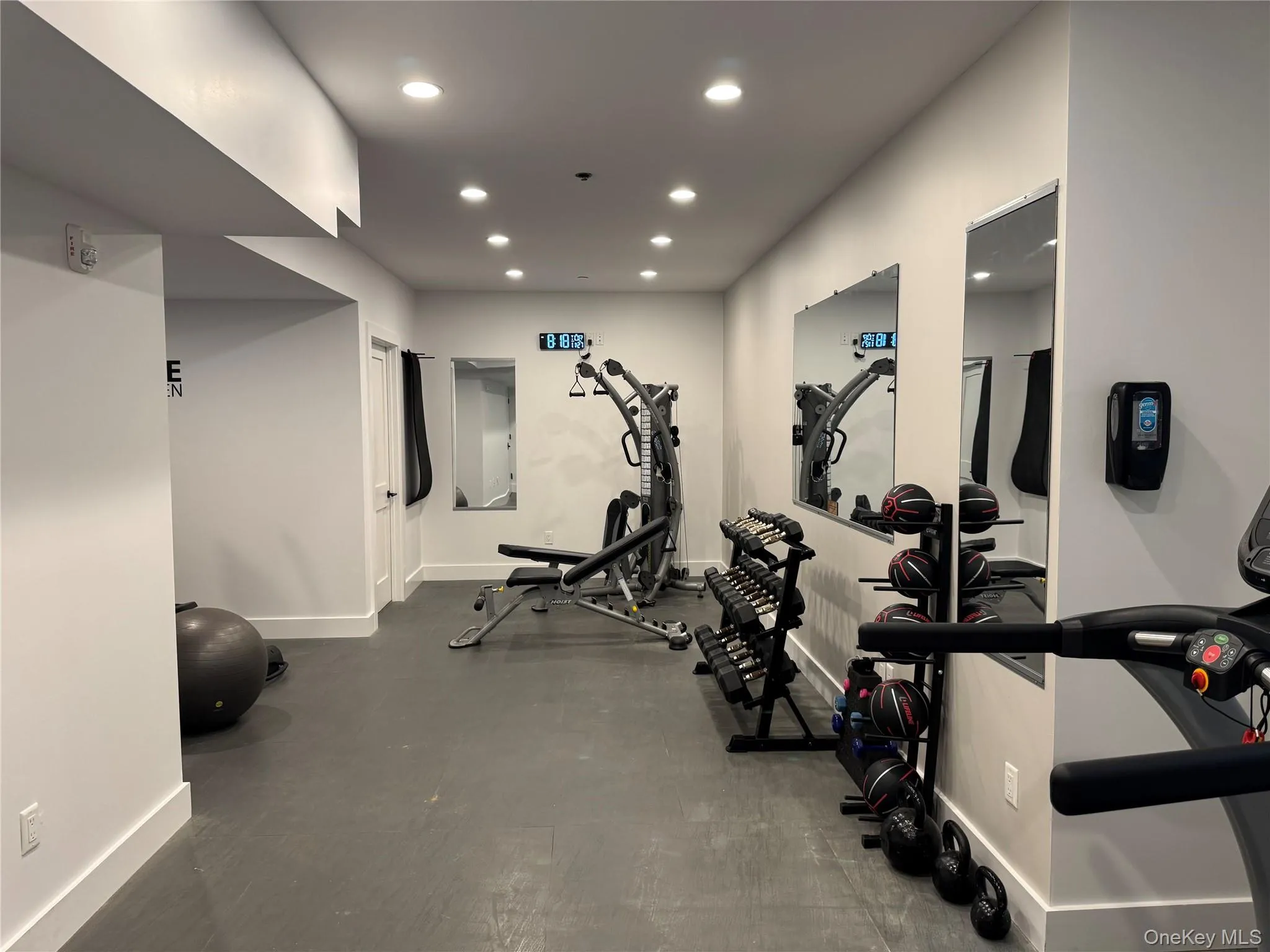 Dedicated fitness space featuring recessed lighting, extensive mirrored walls, and dark-toned flooring Dedicated fitness space featuring recessed lighting, extensive mirrored walls, and dark-toned flooring