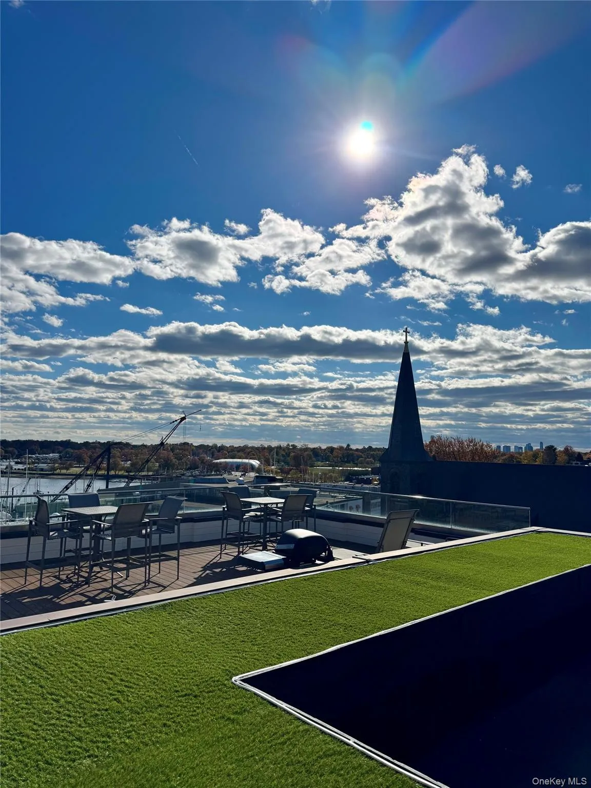 Rooftop terrace featuring artificial turf, composite deck flooring, and glass panel railings Rooftop terrace featuring artificial turf, composite deck flooring, and glass panel railings