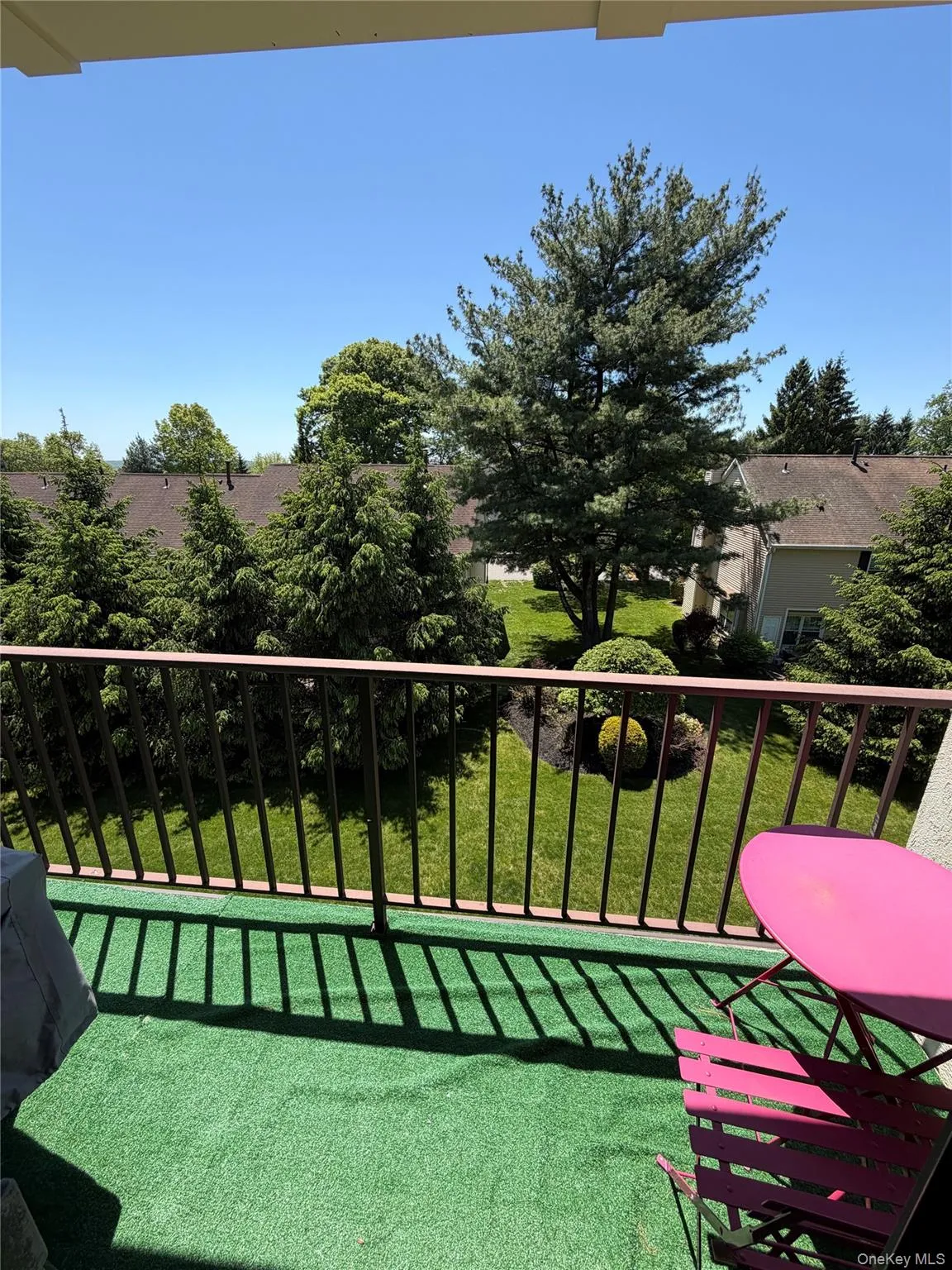 Outdoor balcony featuring green turf flooring and a dark metal railing Outdoor balcony featuring green turf flooring and a dark metal railing