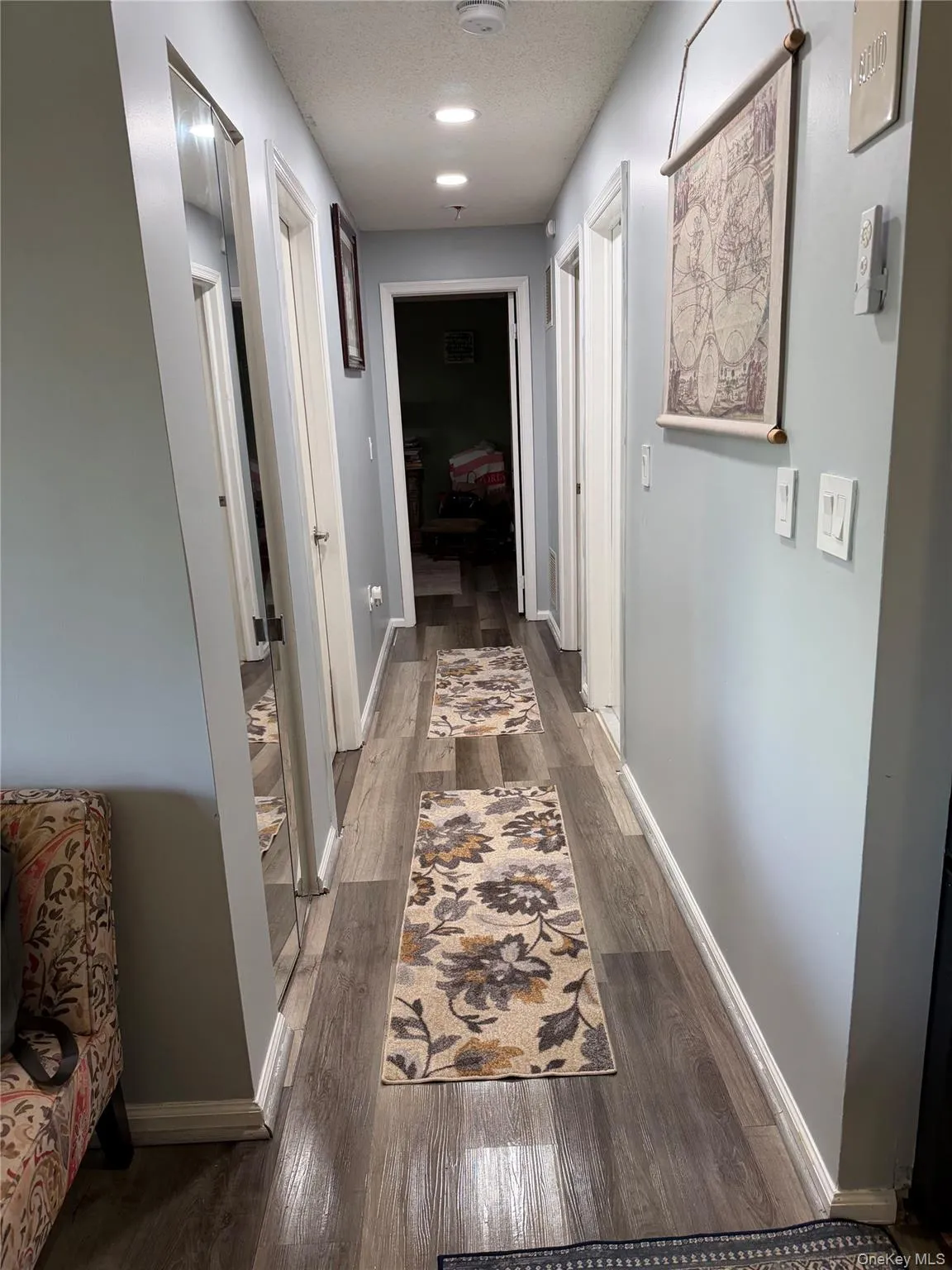 Hallway featuring wood-finish flooring, recessed lighting, light gray wall paint, white trim, and multiple doorways Hallway featuring wood-finish flooring, recessed lighting, light gray wall paint, white trim, and multiple doorways