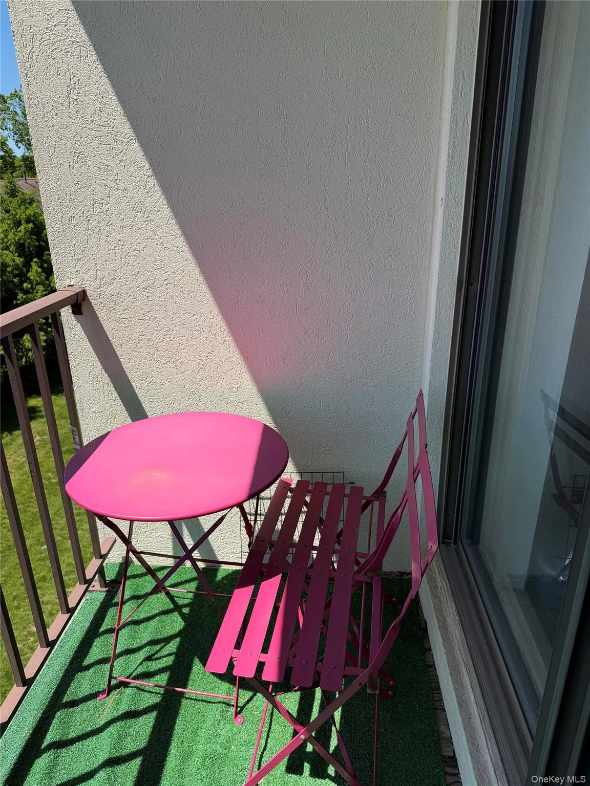 Balcony featuring a metal railing, stucco exterior wall, and a full-height glass door Balcony featuring a metal railing, stucco exterior wall, and a full-height glass door