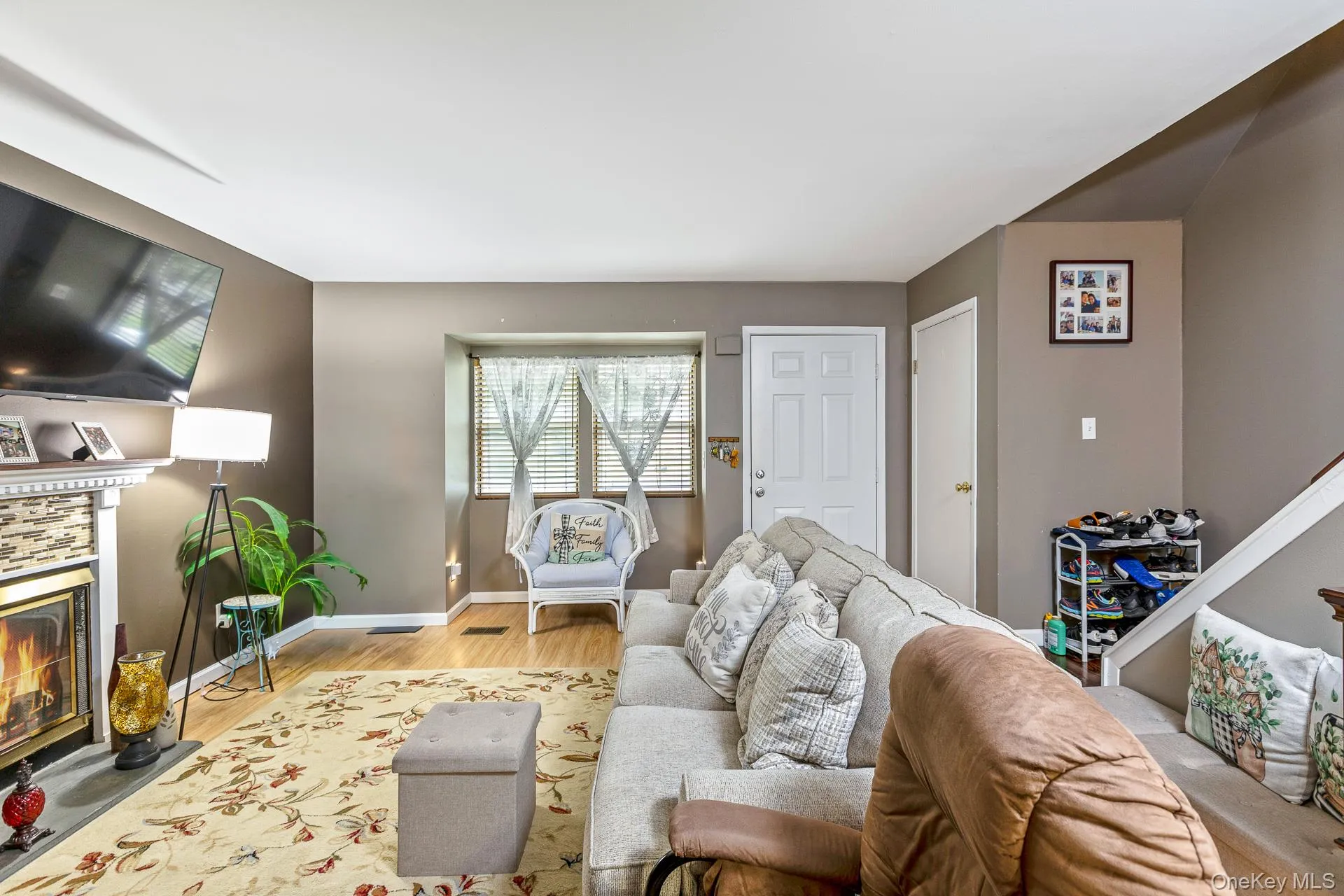 Living area featuring wood-finish flooring and a fireplace with a decorative mantel and stone-look surround Living area featuring wood-finish flooring and a fireplace with a decorative mantel and stone-look surround