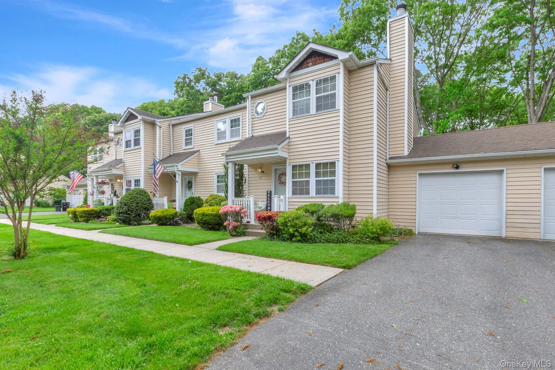 Townhome exterior featuring light-colored siding, a covered entry porch, and a two-story architectural design Townhome exterior featuring light-colored siding, a covered entry porch, and a two-story architectural design
