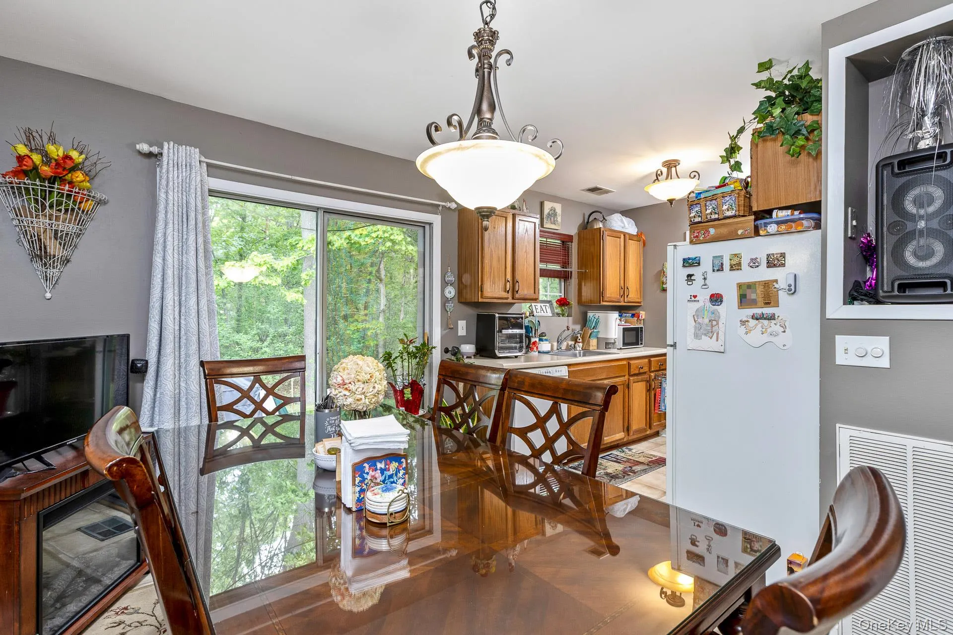 Dining area featuring a sliding glass door, overhead chandelier, and wood-finish dining table Dining area featuring a sliding glass door, overhead chandelier, and wood-finish dining table