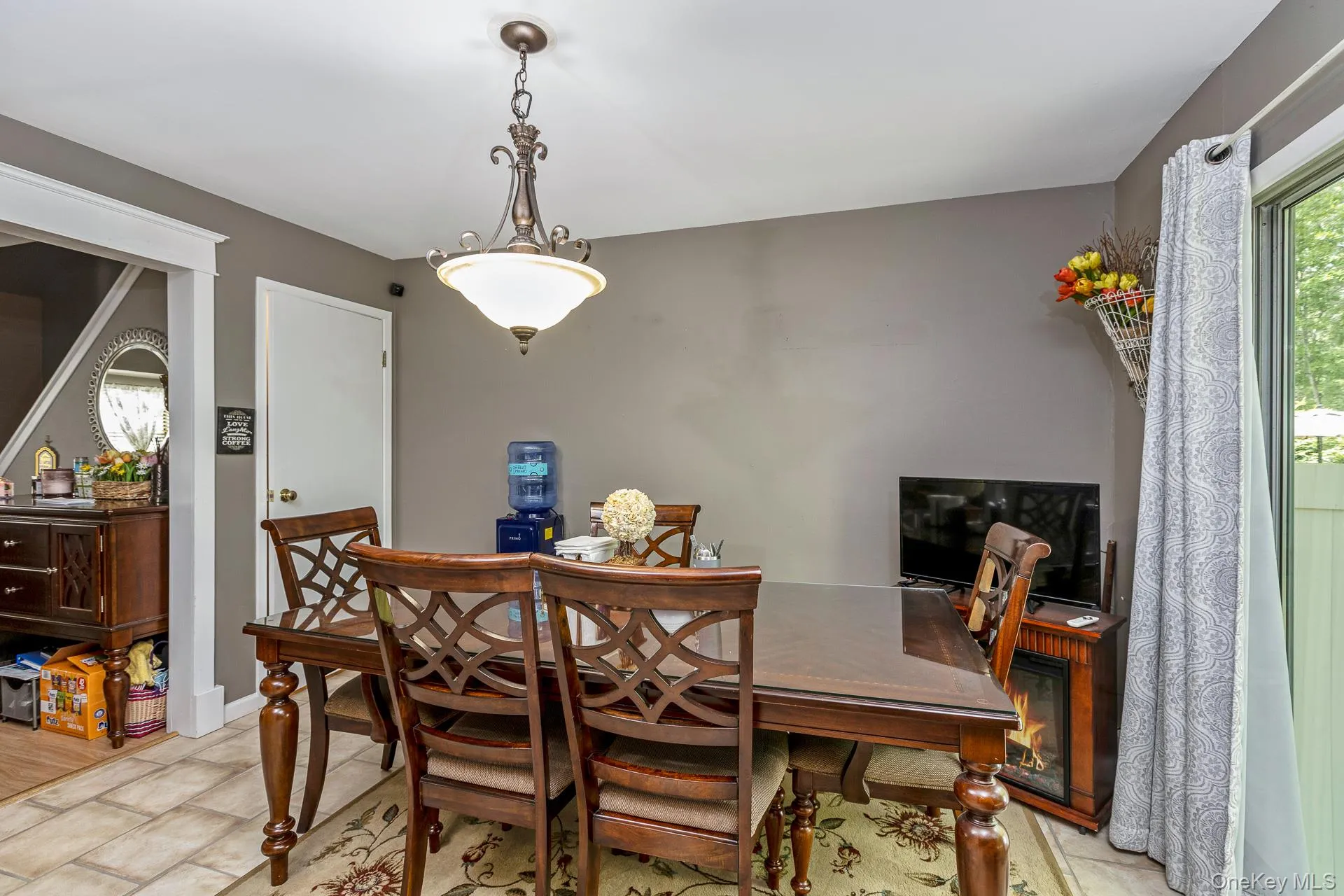 Formal dining space featuring a decorative chandelier, tile flooring, and a sliding glass door to exterior Formal dining space featuring a decorative chandelier, tile flooring, and a sliding glass door to exterior