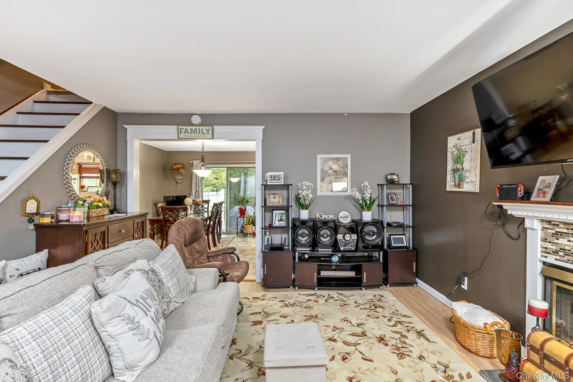 Living room featuring wood-finish flooring, a decorative fireplace with a tile surround, and a framed archway leading to an additional space Living room featuring wood-finish flooring, a decorative fireplace with a tile surround, and a framed archway leading to an additional space