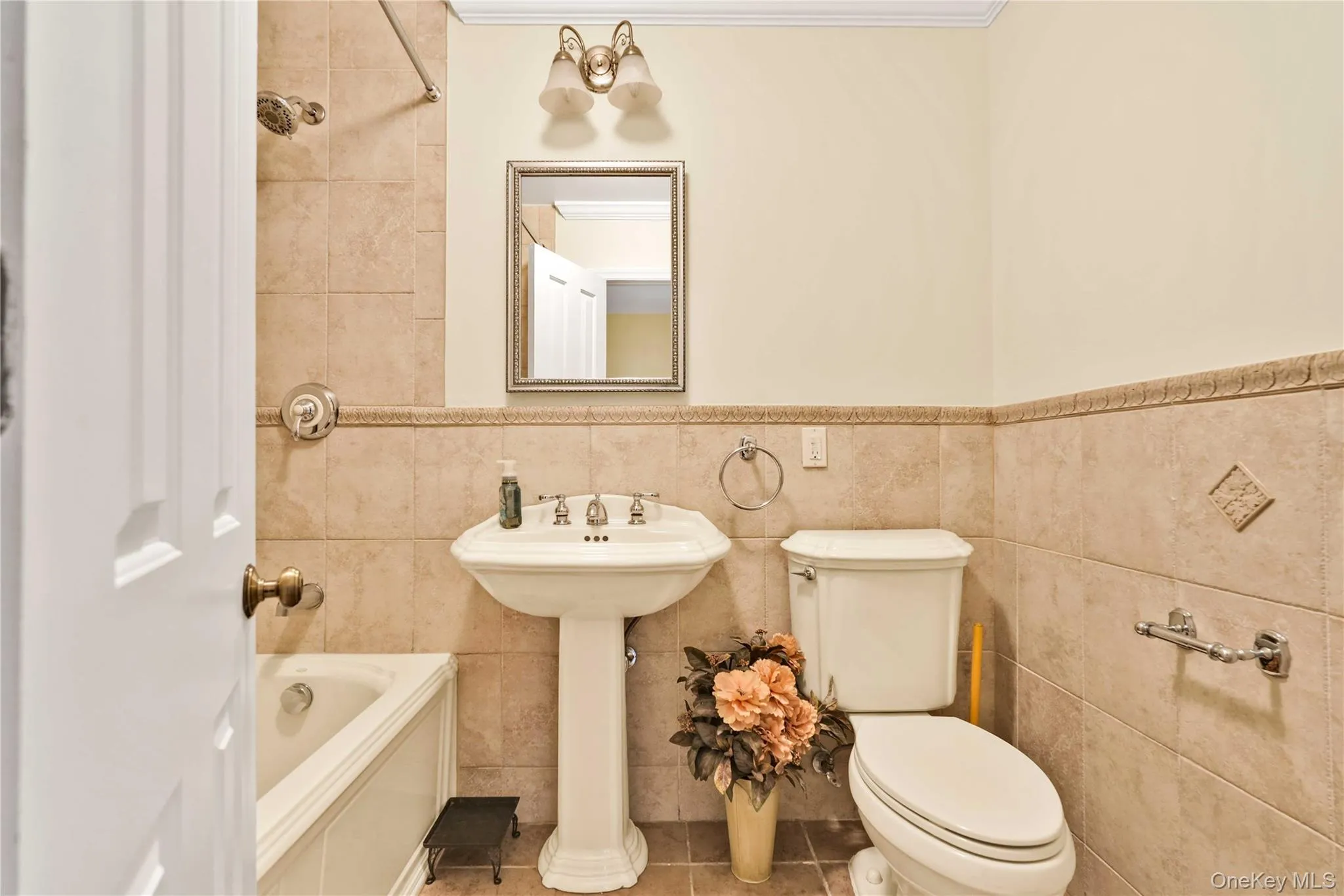 Pedestal sink with brass-toned fixtures, framed mirror, and integrated lighting Pedestal sink with brass-toned fixtures, framed mirror, and integrated lighting