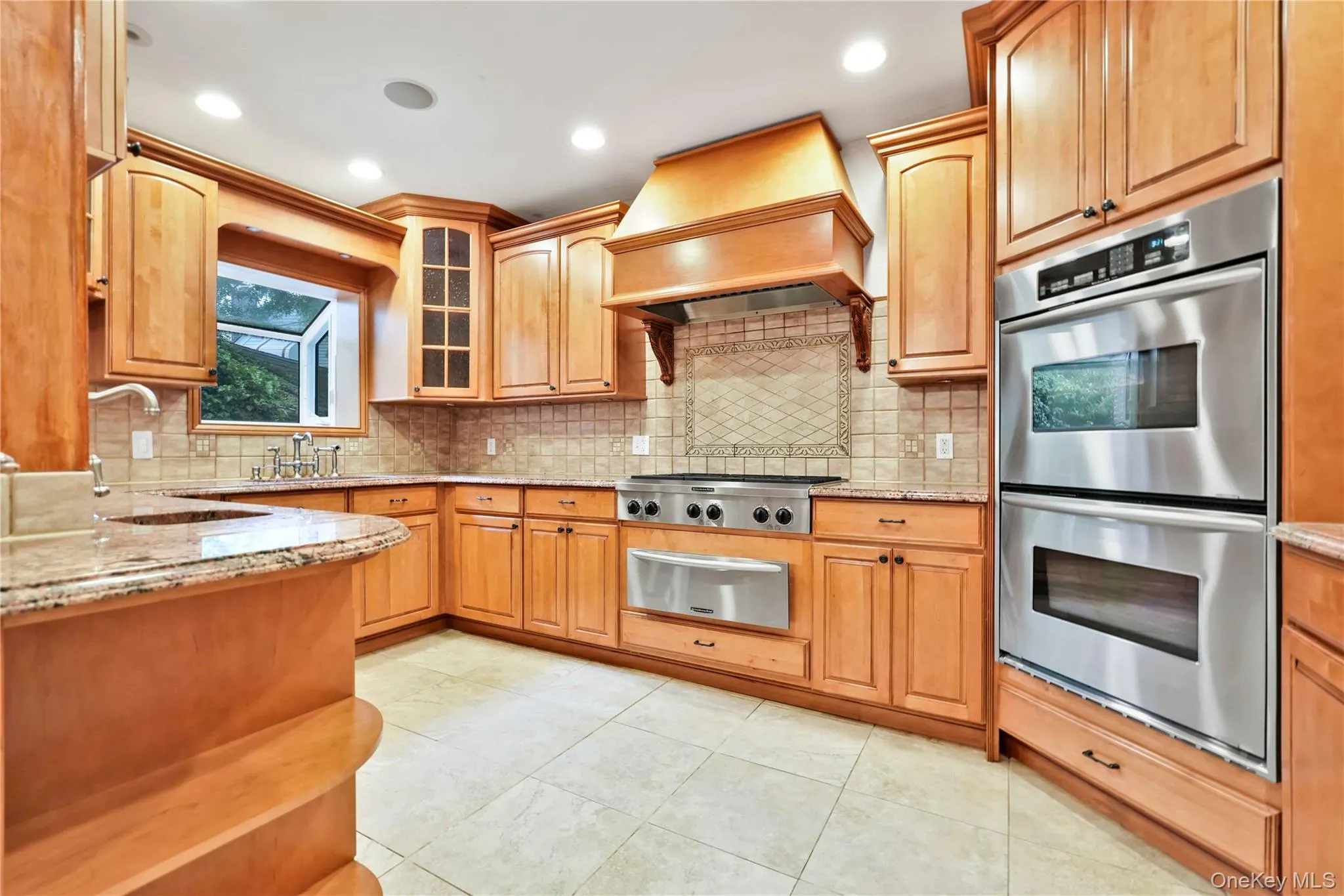 Kitchen featuring light wood cabinetry, granite countertops, a tile backsplash, stainless steel appliances, and recessed lighting Kitchen featuring light wood cabinetry, granite countertops, a tile backsplash, stainless steel appliances, and recessed lighting
