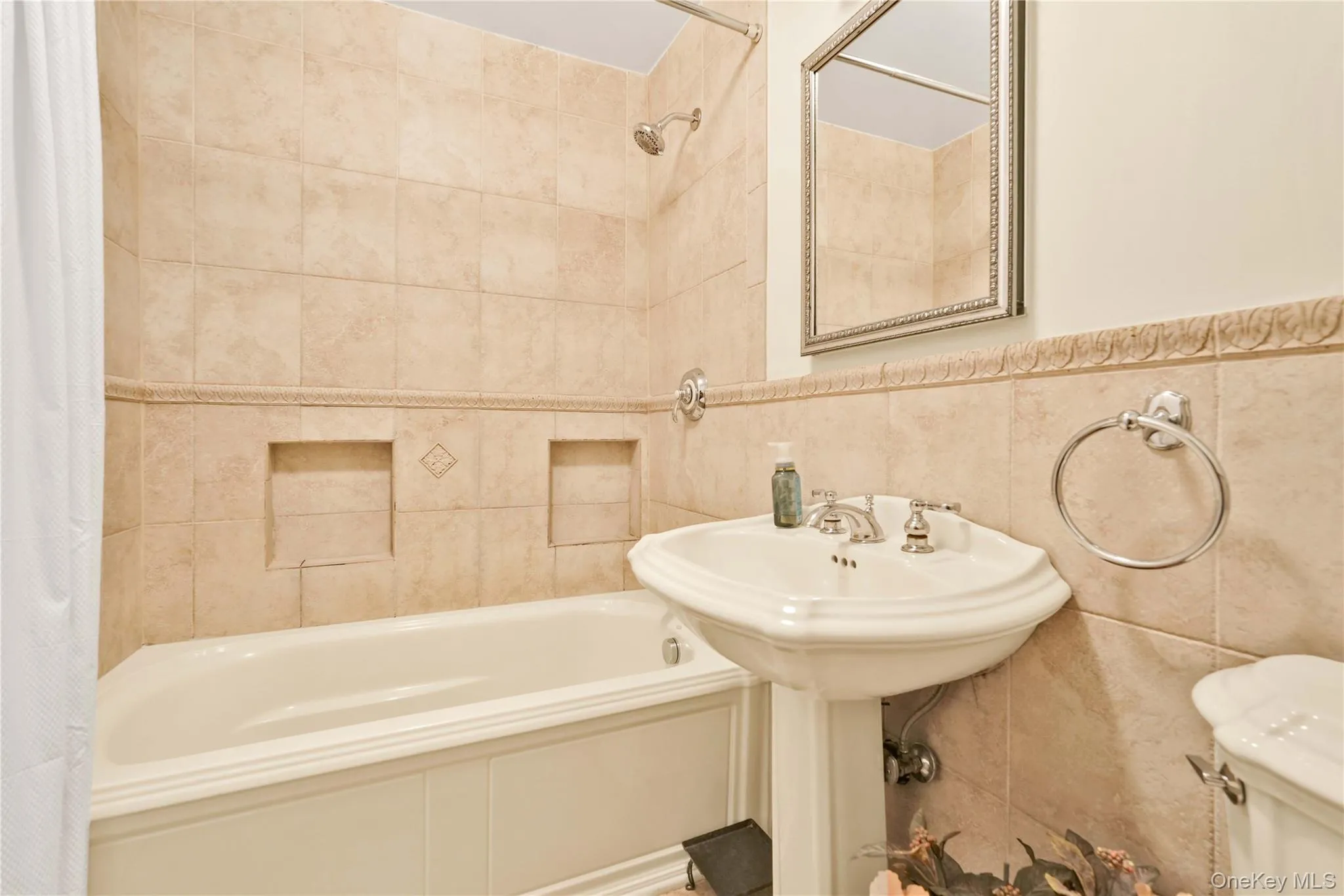 Pedestal sink with chrome fixtures and an ornate framed mirror Pedestal sink with chrome fixtures and an ornate framed mirror