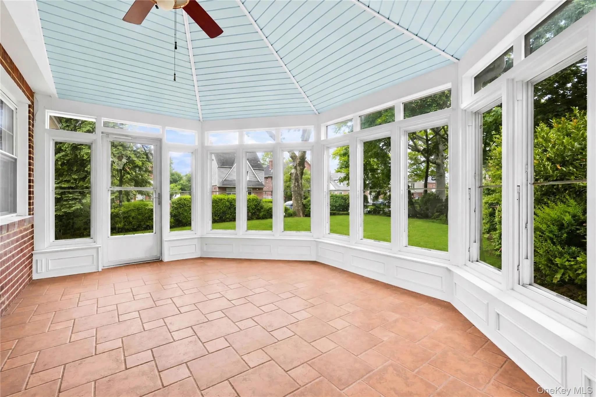 Sunroom featuring a vaulted beadboard ceiling, tiled flooring, floor-to-ceiling windows, and a ceiling fan Sunroom featuring a vaulted beadboard ceiling, tiled flooring, floor-to-ceiling windows, and a ceiling fan