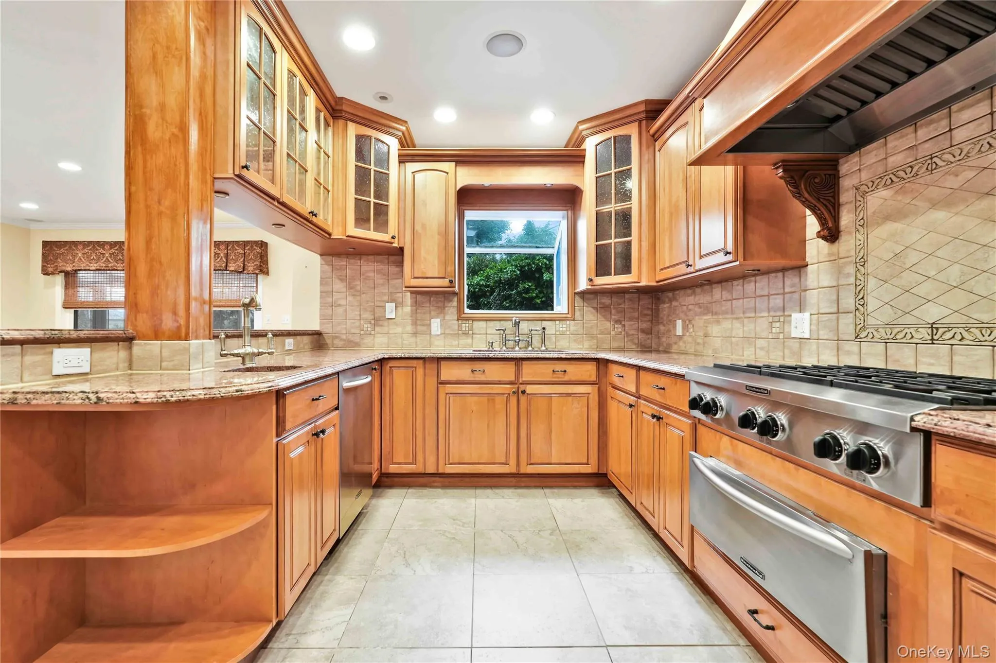 Kitchen featuring light wood cabinetry, granite countertops, stainless steel appliances including a range and dishwasher, and a tiled backsplash Kitchen featuring light wood cabinetry, granite countertops, stainless steel appliances including a range and dishwasher, and a tiled backsplash