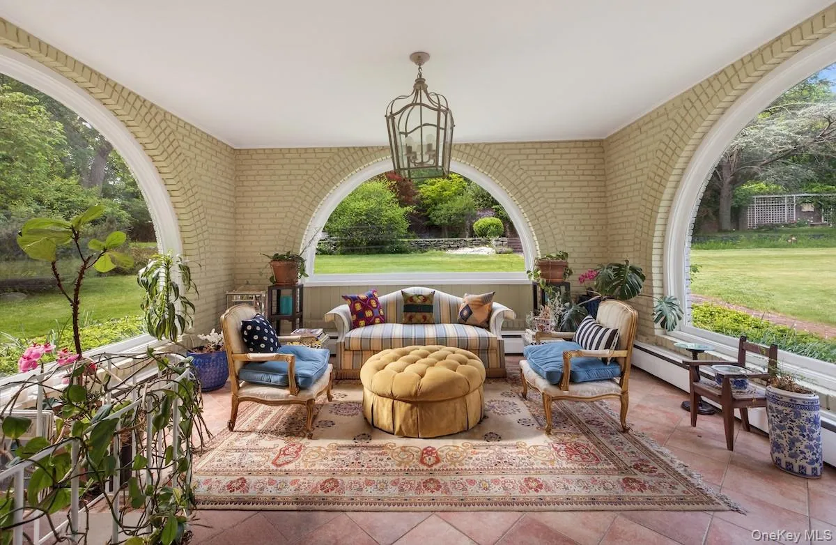 Sun room with oversized arched windows revealing lawn and garden views in three directions Sun room with oversized arched windows revealing lawn and garden views in three directions